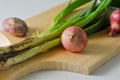 Several stems of onion plants and several whole red onions Royalty Free Stock Photo
