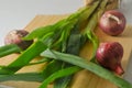 Several stems of onion plants and several whole red onions Royalty Free Stock Photo