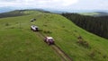 Several SUVs are driving along a mountain road along a dirt road. Aerial view.