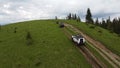 Several SUVs are driving along a mountain road along a dirt road. Aerial view.