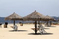 Several teepee hut umbrellas set over tables and chairs at the beach Royalty Free Stock Photo