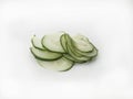 Several thin slices of gherkin stacked on a white background