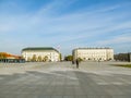 Several tourists walk along the huge empty Pilsudski Square in Warsaw, Poland. City light landscape with copy space, a large