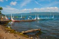 Several traditional Filipino Outrigger boats or `banca` moored at a wooden pier on the shore of Taal Lake, Tagaytay Philippines.