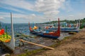 Several traditional Filipino Outrigger boats or `banca` moored at a wooden pier on the shore of Taal Lake, Tagaytay Philippines.