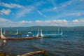 Several traditional Filipino Outrigger boats or `banca` moored at a wooden pier on the shore of Taal Lake, Tagaytay Philippines.