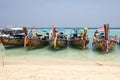 Several traditional Thai boats with tourists stand in a row on a magnificent beach on an island near Phuket Royalty Free Stock Photo