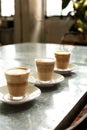 Several transparent cappuccino glasses standing on the table next to each other in line, vertical frame, side view. The concept of