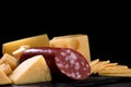 cheese and piece of salami loaf are on black background