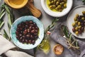 Several Varieties Of Fresh Olives In Different Ceramic Plates On An Old Vintage Gray Table Concrete Background. Natural Product Co