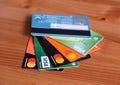 Several Visa and Mastercard bank cards lie like a fan on a wooden surface