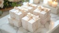 Stacked white gift boxes with cream ribbons on marble surface near candles and flowers Royalty Free Stock Photo