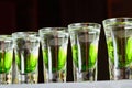 Several white-green alcoholic drinks shots on the bar counter