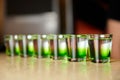 Several white-green alcoholic drinks shots on the bar counter. Close-up, selective focus