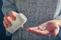 Several white round tablets (vitamins) on a woman's palm, a white plastic bottle for pills in her hand. Royalty Free Stock Photo