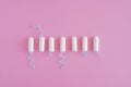 Several white sanitary tampons on a pink background.