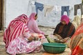 Several women in front of their house, separating the wheat from the weeds to get ready to grind it.