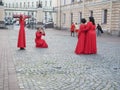 Several women in identical red dresses taking photos of each other against the background of the sights of St. Petersburg. Russia.