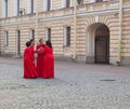 Several women in identical red dresses talk to each other gathered in a circle. Saint-Petersburg. Summer 2017