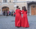 Several women in identical red dresses talk to each other gathered in a circle. Saint-Petersburg. Summer 2017