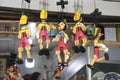 Several wooden pinocchio puppets in colorful costumes hanging on a rope on sale in the store Royalty Free Stock Photo