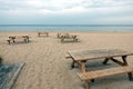 Several wooden tables and benches on empty sandy beach in Jurmala seacoast in low season