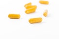 Yellow capsules scattered on a white surface with soft focus Royalty Free Stock Photo