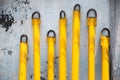 several yellow poles on a concrete wall with some dirt in them