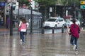 Several young people run to shelter from the rain