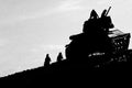 several youths playing on abandoned tank in silhouette