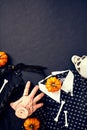 Severed hand Thing from Addams Family, Wednesday dress and hair braids, spiders, bones, orange pumpkins on dark background.