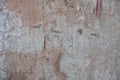 Severely damaged old concrete wall with peeling pink paint and deep cracks. rough surface texture Royalty Free Stock Photo
