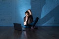 Teenager man suffering Internet cyber bullying sitting alone with computer feeling hopeless