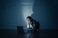 Teenager man suffering Internet cyber bullying sitting alone with computer feeling hopeless