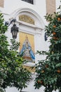Commemorative icon on a building in Seville, Spain. Framed by trees, selective focus