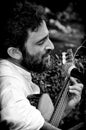 Close up bearded mature man playing guitar in street