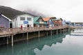 A man in a red jacket walks along the boardwalk at the small boat harbour with colorful historic buildings in the background at