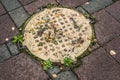 Sewer cast iron manholes on sidewalk. Wet metal is covered with yellow autumn leaves after rain. Time of repair Royalty Free Stock Photo