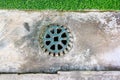 Sewer grate on concrete drain floor. Clogged street drain. Sewer cover. Metal sewer cover