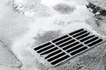 Sewer grate on wet road with puddles