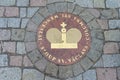 Sewer manhole with golden crown on cobblestone road Royalty Free Stock Photo