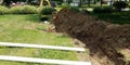 Sewer pipe replacement with trench and machinery in lawn Royalty Free Stock Photo