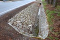 Sewer pipes under the bridge. crossing the ditch by the road. concrete hole with stone paving surroundings. The gutter drains arou Royalty Free Stock Photo