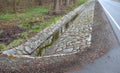 Sewer pipes under the bridge. crossing the ditch by the road. concrete hole with stone paving surroundings. The gutter drains arou Royalty Free Stock Photo