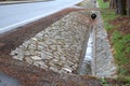 Sewer pipes under the bridge. crossing the ditch by the road. concrete hole with stone paving surroundings. The gutter drains arou Royalty Free Stock Photo