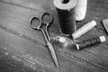 Sewing accessories: bobbins of thread, scissors, needle, thimble on wooden table. Black and white photo. Tailoring and Royalty Free Stock Photo