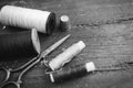 Sewing accessories: bobbins of thread, scissors, needle, thimble on wooden table. Black and white photo. Tailoring and Royalty Free Stock Photo