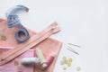 Sewing accessories and pink fabric on a white background. Fabric, sewing threads, zipper, needle, buttons and sewing centimeter.