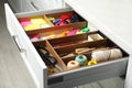 Sewing accessories and stationery in open desk drawer