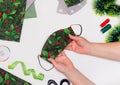 Sewing Christmas Face Mask with Holly Pattern flat lay. Top view Taylor hands . DIY and Handmade